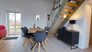 Un salon moderne avec un coin repas, un escalier et un canapé rouge.