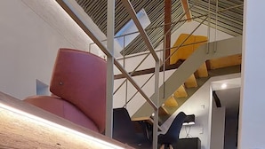 Un intérieur moderne avec un aquarium en verre, des marches en bois et un escalier doté d’une rampe en métal.