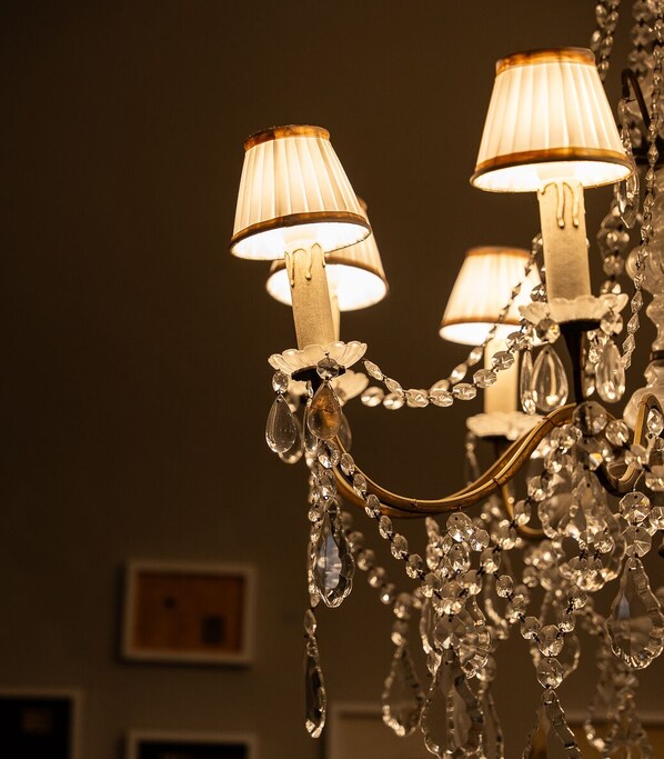 A chandelier with multiple lamps and crystal decorations. - Il duomo suites (Pietrasanta)