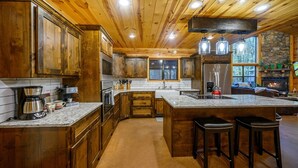 Una cocina amplia con armarios de madera, una isla grande con taburetes y una chimenea de piedra.