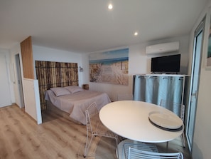 A bedroom with a bed, a dining table, and a TV.