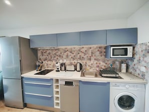 A compact kitchen with a microwave, toaster, sink, and dishwasher.