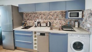 A compact kitchen with a dishwasher, washing machine, microwave, and a sink.