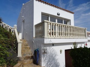 Stunning two-story building with a balcony and balustrade, featuring a small window and door.