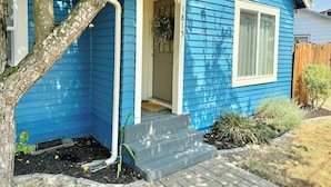 Ein blaues Haus mit weißer Tür und Stufen zum Eingang.