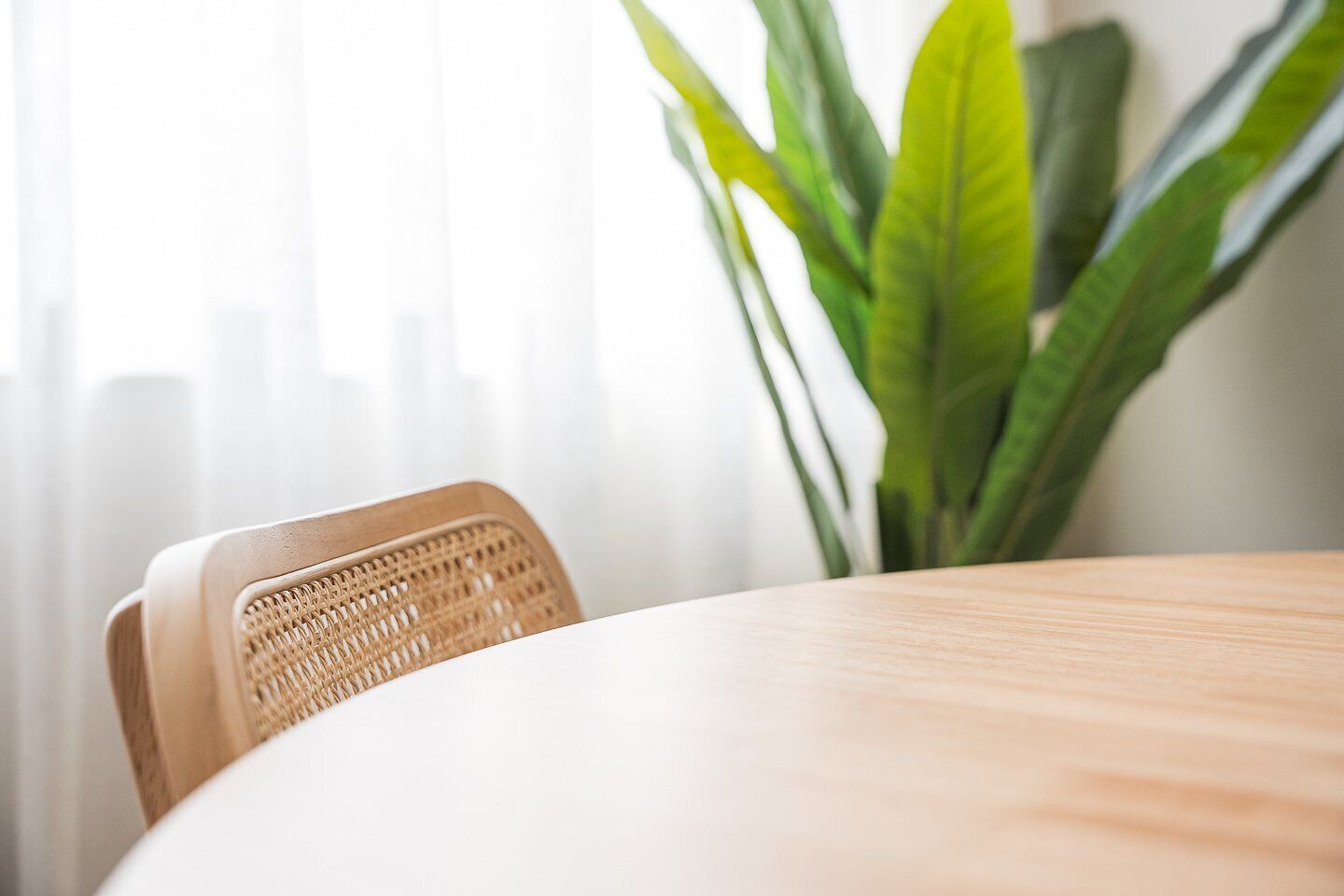 Una mesa redonda de madera con una silla trenzada al frente.
