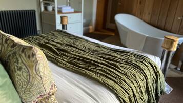 Een bed met een gekleurd kussen, een groene deken en een witte matras.