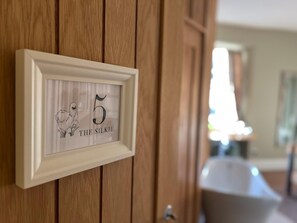 A framed number 5 sign with a dog illustration and the text 'THE SILKIE' on a wooden wall. - The Roost  (Cullompton)