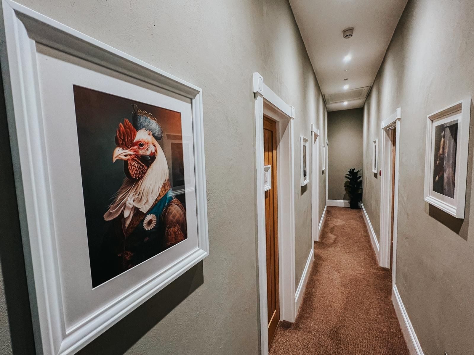 A hallway with framed artwork on the walls, carpeted flooring, and doors leading to other rooms.
