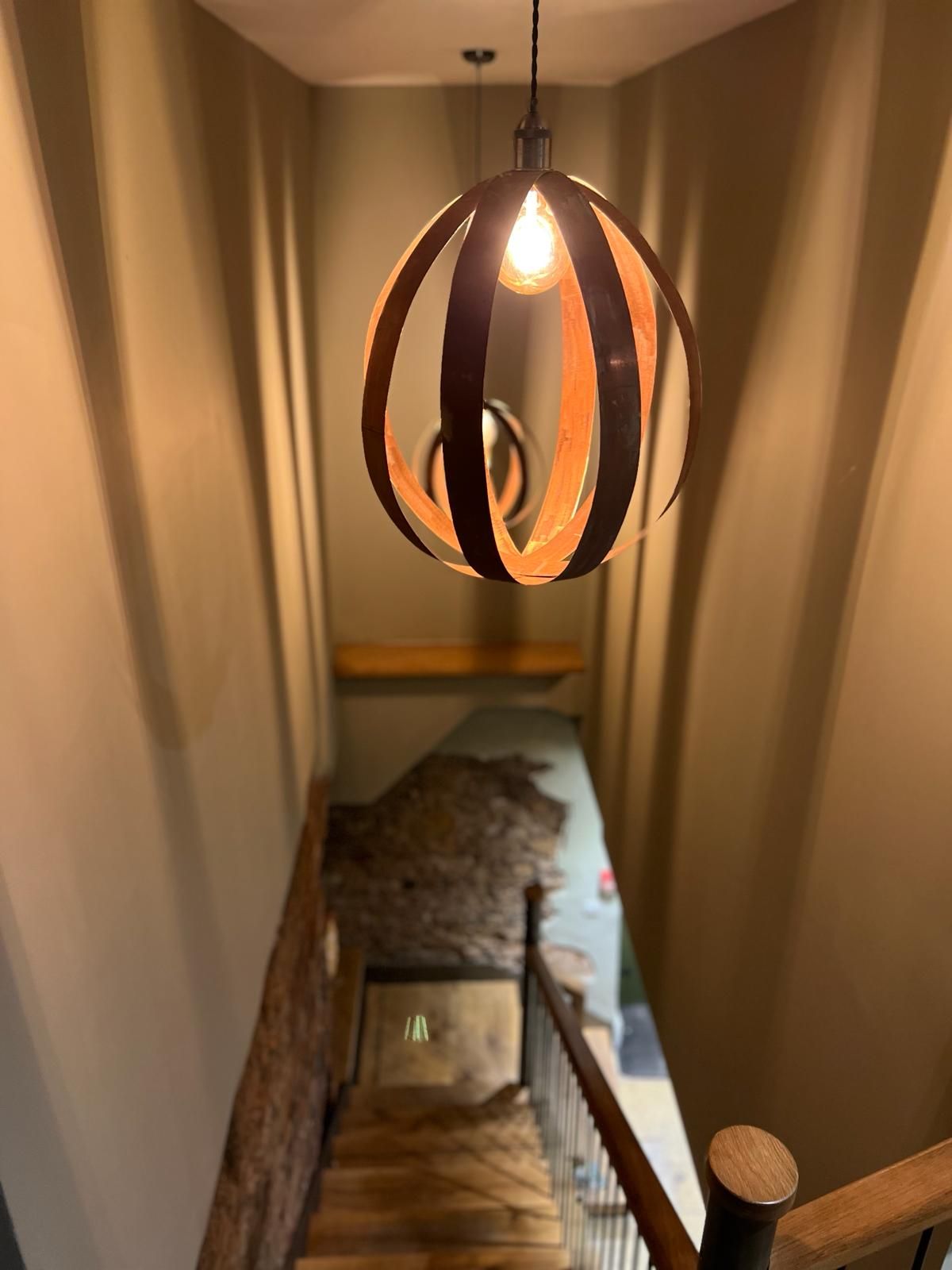 A staircase with a wooden handrail and a metal railing, leading to a bedroom with a bed and a nightstand.