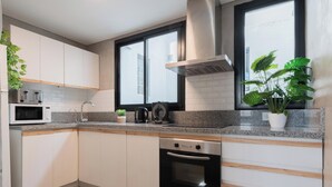 Une cuisine moderne avec des meubles blancs, un four à micro-ondes encastré, une machine à café et un lave-vaisselle.