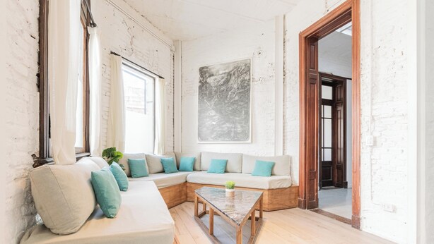 Un salon moderne avec un canapé d’angle, une table basse et un grand tableau abstrait accroché au mur.