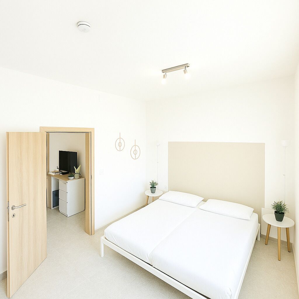 Una camera da letto moderna con un letto grande, una scrivania con un televisore e un tavolino con una pianta.