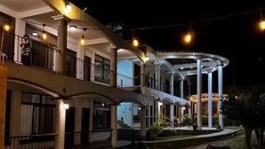 A multi-story hotel with balconies, outdoor seating, and string lights.