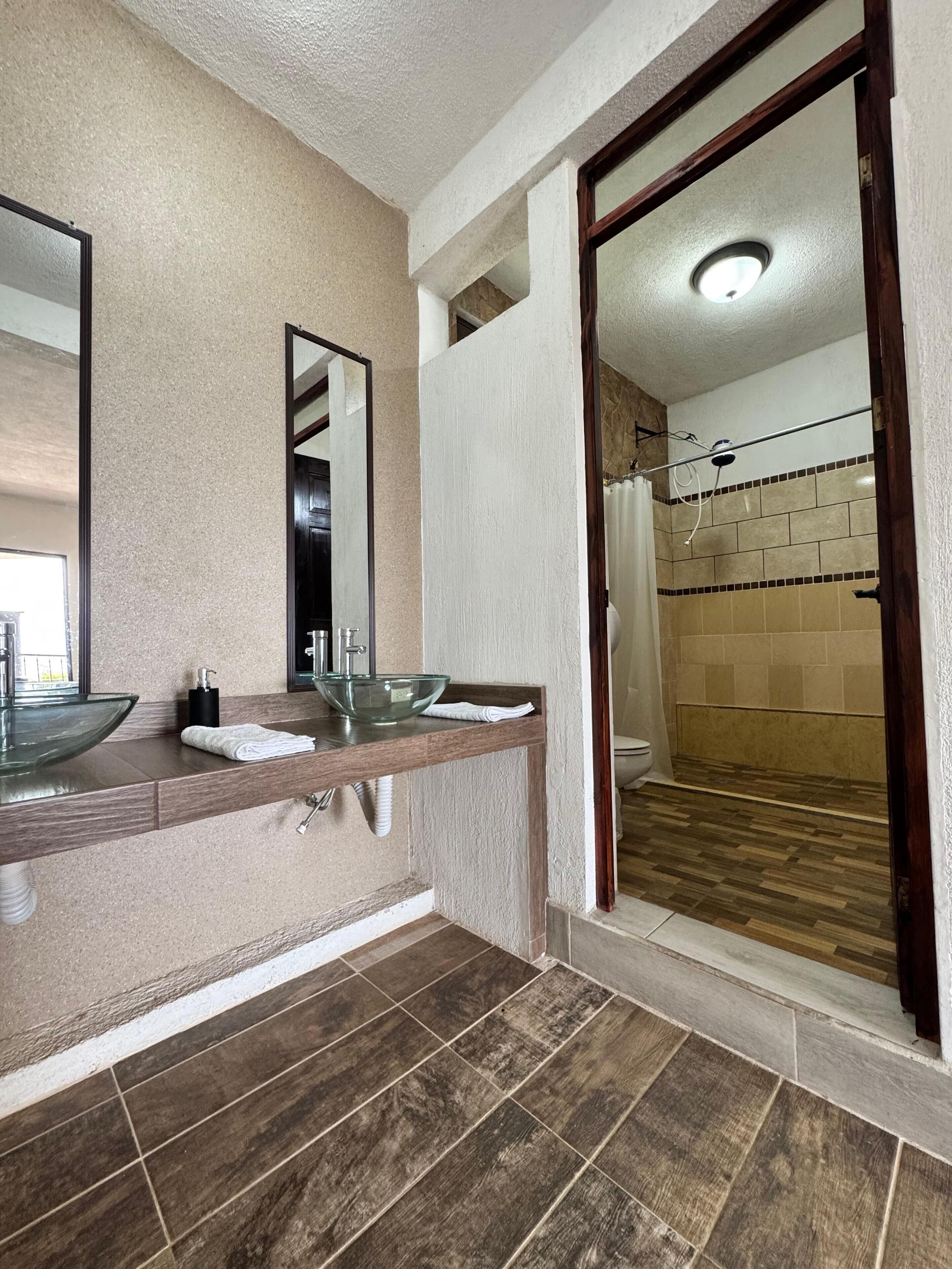 Een moderne badkamer met een glazen wastafel, een spiegel en een douche.
