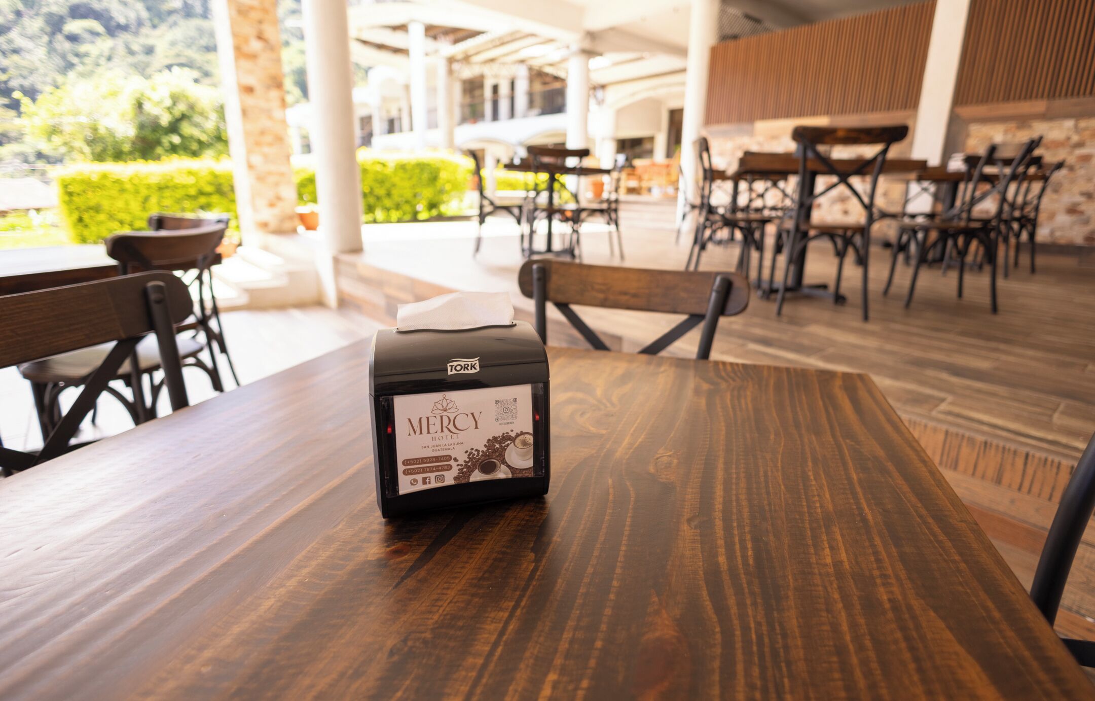 A wooden table with a coffee machine labeled 'Mercy Hotel' in a cafe setting.