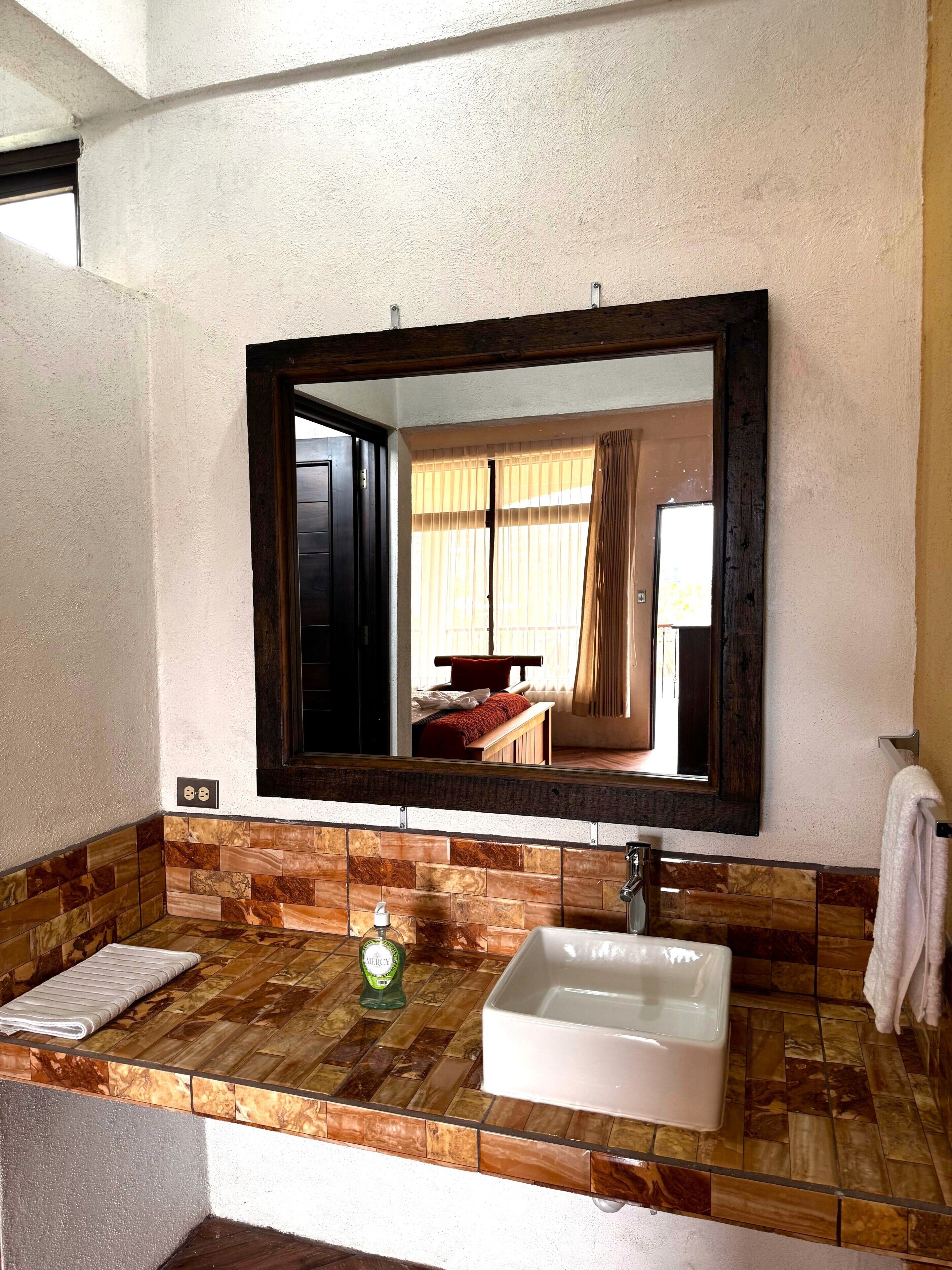 A bathroom with a wooden vanity, a white sink, and a large mirror.