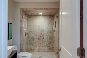 A bathroom with a toilet, a sink, a shower with a glass door, and a mirror. - Beachfront Ocean Dream on the Sand (Hilton Head Island)