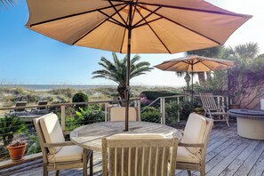 A wooden deck with outdoor seating and umbrellas, overlooking a beach. - Beachfront Ocean Dream on the Sand (Hilton Head Island)
