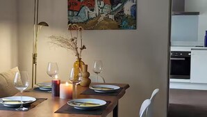 Comedor con una mesa dispuesta para dos personas, una vela y un florero con flores secas.