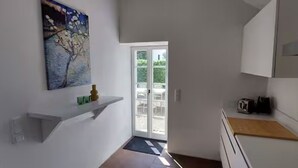 Una cocina moderna con armarios blancos, una encimera de madera y un cuadro en la pared.