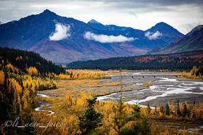 Un paisaje montañoso con un río y árboles de colores otoñales.