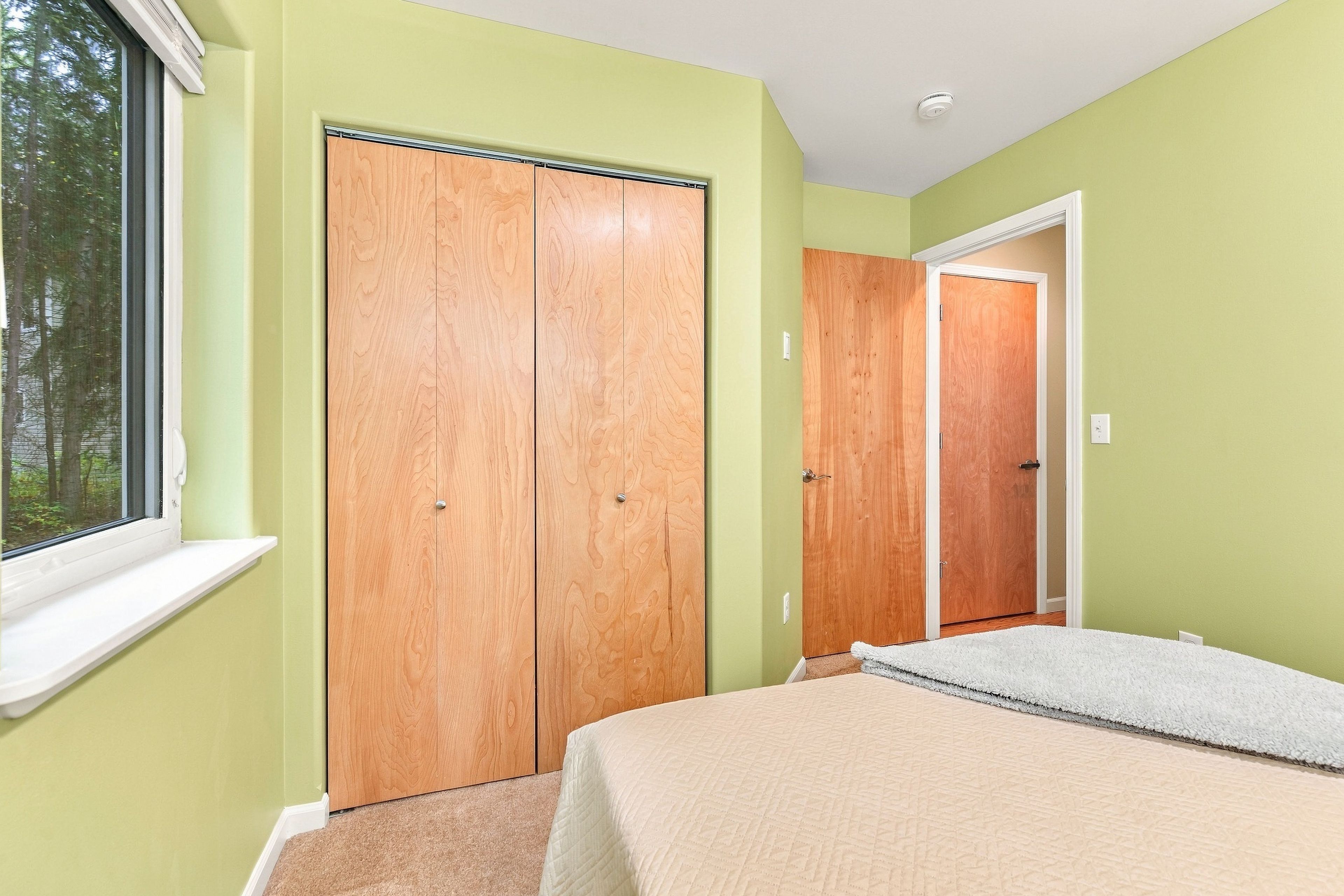 Une chambre à coucher avec un lit, une fenêtre et deux armoires en bois.