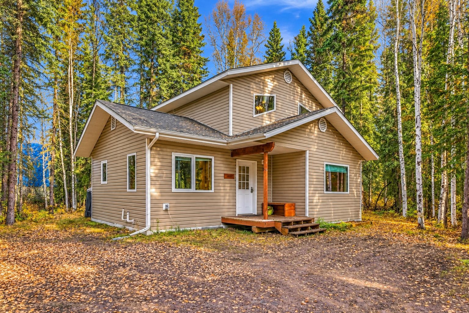 Une cabane à deux étages avec un porche, entourée d’une forêt.