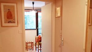 Un pasillo con piso de madera, una puerta a la derecha y un ventanal al fondo.
