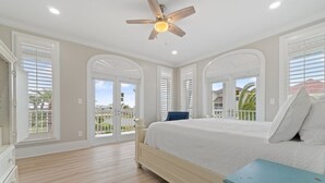 Une chambre avec un grand lit, un ventilateur de plafond et une vue sur l’extérieur.