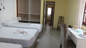 A hotel room with two beds, a desk, a chair, and a wardrobe.
