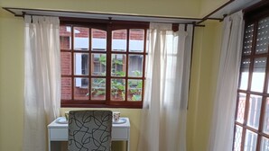 A corner room with a dining table, a chair, and a window with curtains.
