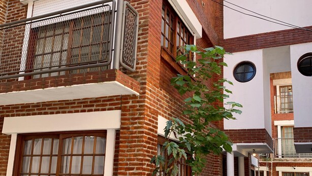A multi-story building with brick facades, large windows, and a gated entrance.