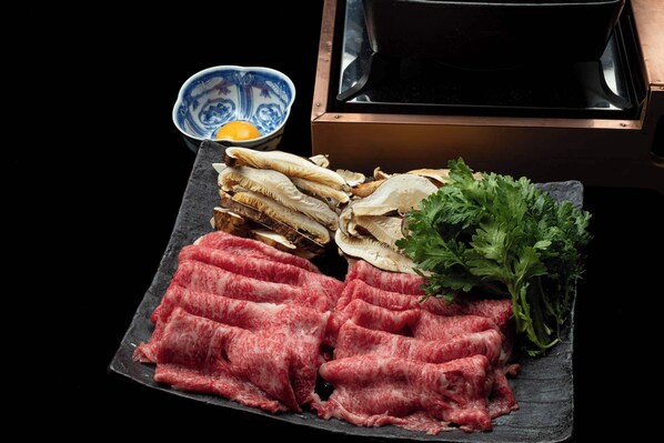 A black slate serving board with raw meat, mushrooms, and parsley. - Tsurumaki Onsen Motoyu Jinya (Hadano)