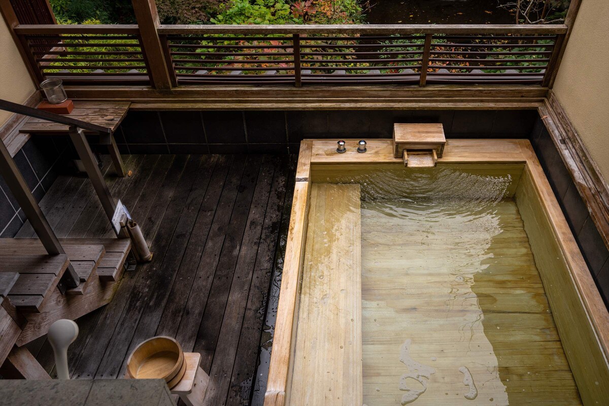 Un área de baño de madera con un banco de madera y una pequeña bañera de madera.