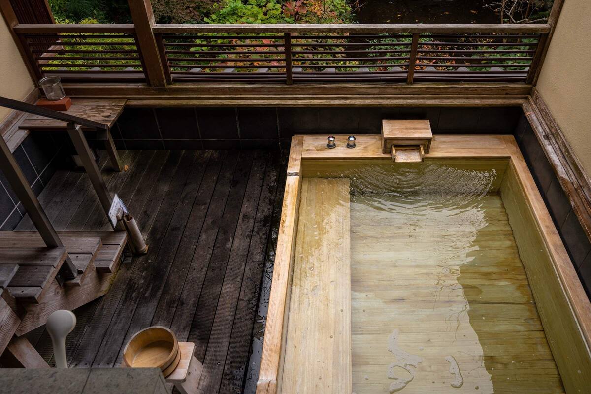 Een badruimte van hout met een houten bankje en een klein houten bad.