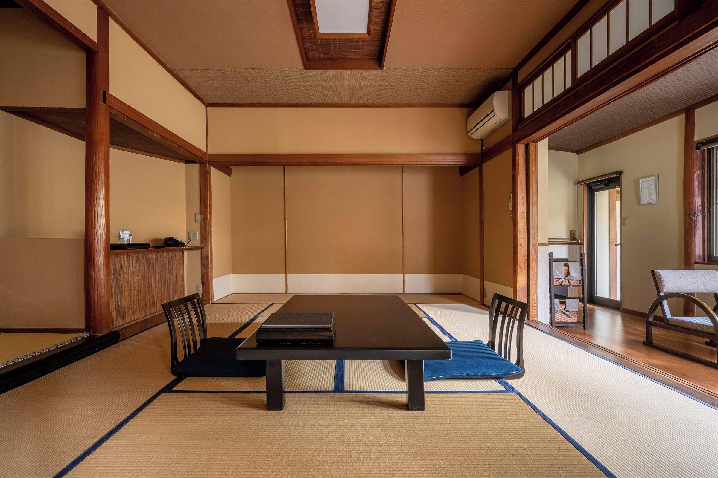 A traditional Japanese room with tatami flooring, a low table, and wooden furniture.