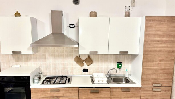 A modern kitchen with white cabinets, a stainless steel sink, a built-in oven, and a gas stove. - Top Apartment 2 (Castel D'Azzano)