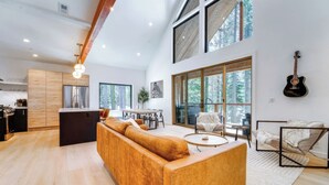 Amplia sala de estar con un sofá grande, una mesa de comedor y una cocina al fondo.