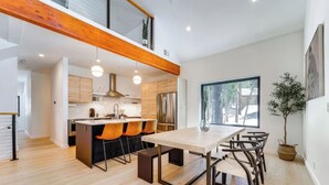 Una cocina moderna con una isla central, vigas de madera en el techo y un amplio ventanal.