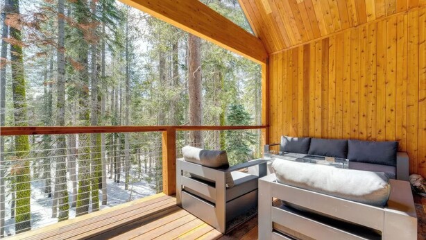 Una cabaña de madera con balcón que da a un bosque.