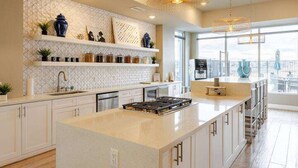 Une cuisine moderne avec des meubles blancs, un îlot central et des luminaires suspendus.