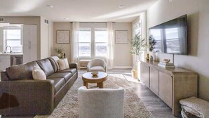 Un salon spacieux comprenant un canapé, des fauteuils, une table basse et un téléviseur.