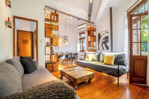 A cozy living room with a sofa, coffee table, and a wooden bookshelf.