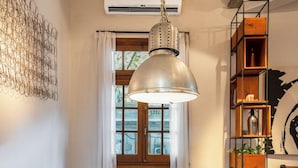 A dining area with a long wooden table, clear chairs, a hanging pendant light, and a bookshelf with various items. - MOT Dorrego 2200 (Buenos Aires)