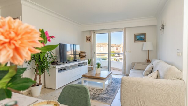 A modern living room with a sofa, a coffee table, a TV, and a balcony with a view. - Proche Thalazur et plages, Parking privé, Piscine (Antibes)