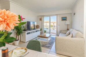 Una sala de estar moderna con un sofá, una mesa de centro, un televisor y un balcón con vistas.