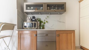 A compact kitchen with wooden cabinets, a built-in microwave, and a small countertop area. - Proche Thalazur et plages, Parking privé, Piscine (Antibes)