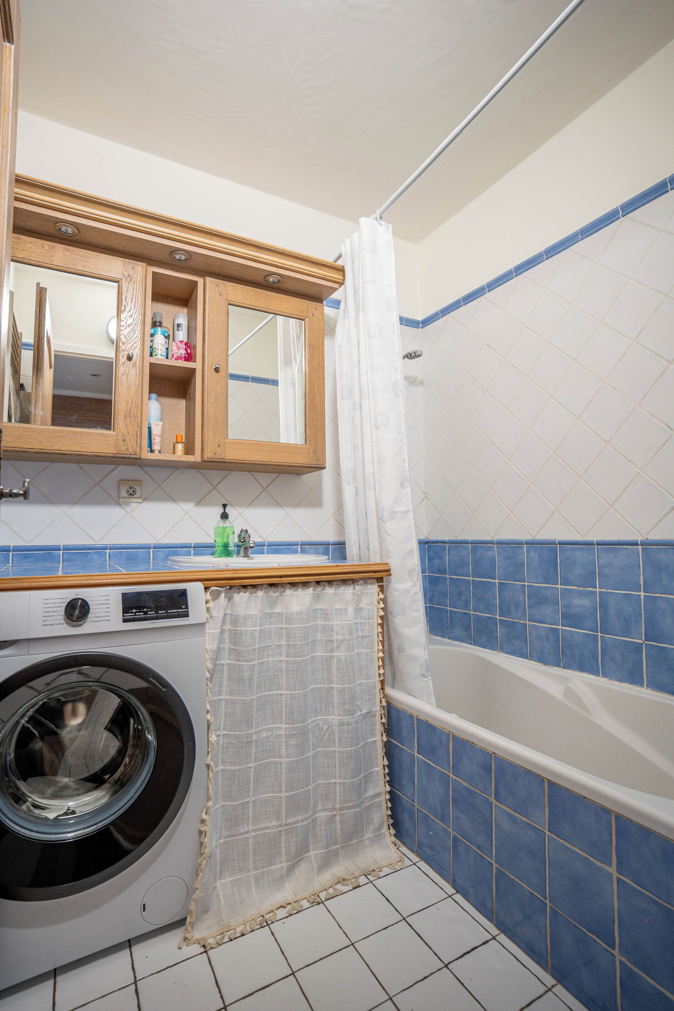 Casa de banho com máquina de lavar roupa, banheira e cortina de chuveiro.