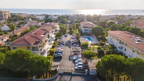 An aerial view of a residential area with a row of parked cars, a swimming pool, and buildings with red-tiled roofs. - Proche Thalazur et plages, Parking privé, Piscine (Antibes)